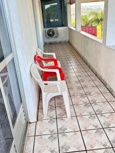 two red and white chairs sitting on a porch at Quarto confortável em Imbituba in Imbituba +9 photos