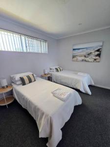 two beds in a room with white walls at Oasis Mandurah Resort in Mandurah