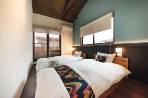 two beds in a room with two windows at 華ならまち in Nara