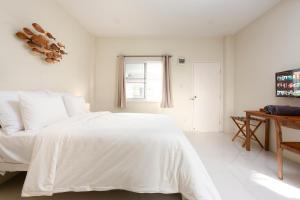 a white bedroom with a white bed and a desk at Comfy Corner Hotel in Chiang Mai