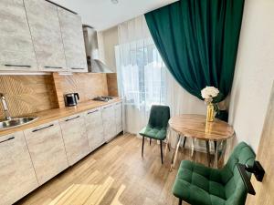 a kitchen with a table and two green chairs at Бухар -Жырау 72 in Karagandy