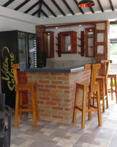 a bar with wooden chairs and a brick wall at Hotel Campestre Villa Salome in Quimbaya