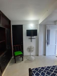 a bedroom with a green chair and a flat screen tv at Hospedaje Brisas del Mar 1A in San Andrés