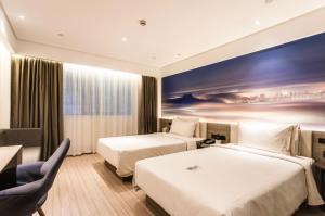two beds in a hotel room with a painting on the wall at Atour Hotel Nanjing Xinjiekou Daxinggong Subway Station in Nanjing