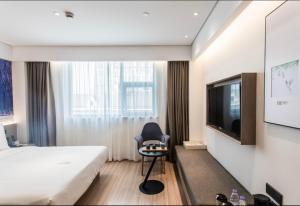 a bedroom with a bed and a chair and a tv at Atour Hotel Nanjing Xinjiekou Daxinggong Subway Station in Nanjing