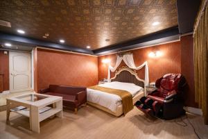a bedroom with a bed and a chair and a table at ホテルパティオ in Suwa