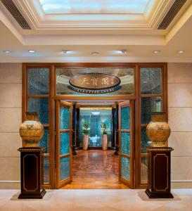 a lobby with glass doors and vases on pillars at The St. Regis Beijing in Beijing