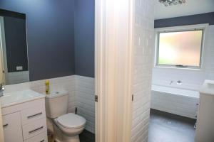 Un baño con inodoro, lavabo y bañera. en Decked Out At Bright, en Bright 24 fotos más