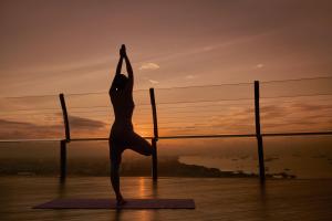 a woman doing a yoga pose in front of the sunset at Marina Bay Sands in Singapore