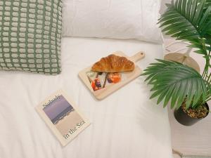 a plate of food on a bed with a book and a plant at Sha lala stay in Seoul