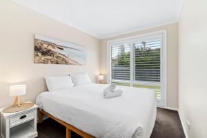 a bedroom with a white bed and a window at Light and Bright at Maloneys in Maloney's Beach