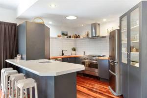 a kitchen with stainless steel appliances and wooden floors at Paradise Near Palm Beach in Palm Beach