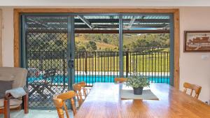 a dining room with a wooden table and a large window at Barkeldine Farm Country Retreat in Bucca-Wauka