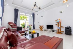 ein Wohnzimmer mit einem Ledersofa und einem TV in der Unterkunft Sun Villa 4A - Loa Karaoke - Sân Vườn - Hồ Bơi To - Gần Biển - Ghế Massage in Vũng Tàu
