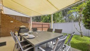 コフスハーバーにあるCoffs Harbour Beach Escape -Pet Friendly, Pool, Spa, Tennis, Near Beachの裏庭の木製テーブルと椅子