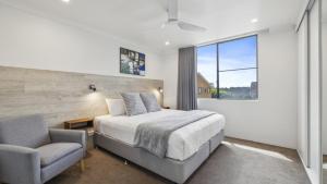 コフスハーバーにあるCoffs Harbour Beach Escape -Pet Friendly, Pool, Spa, Tennis, Near Beachのベッドと椅子と窓のある寝室