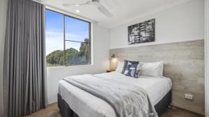 コフスハーバーにあるCoffs Harbour Beach Escape -Pet Friendly, Pool, Spa, Tennis, Near Beachの大きなベッドと窓のある寝室