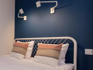 a bedroom with a blue wall and a bed with pillows at 1 min from Main Square I Budget Apartment in Gliwice