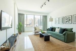 een woonkamer met een groene bank en een tv bij Frank Porter - Madina Tower in Dubai