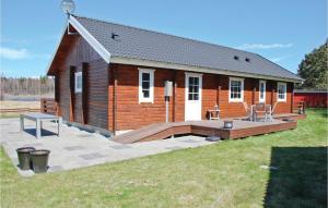 a large wooden cabin with a deck in the yard at Holiday Home Kærsangervej Ebeltoft in Øksenmølle