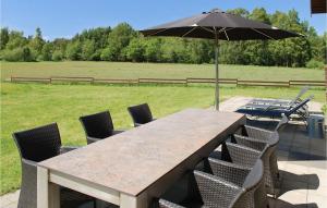 a wooden table with chairs and an umbrella at Holiday Home Kærsangervej Ebeltoft in Øksenmølle