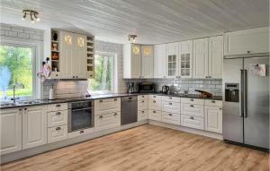 eine Küche mit weißen Schränken und Geräten aus Edelstahl in der Unterkunft Nice Home In Norra Kedum With Wifi in Norra Kedum