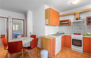 a kitchen with orange cabinets and a table with chairs at Awesome Apartment In Punat With Wifi in Punat