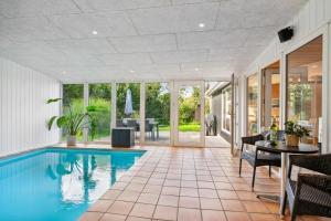 a swimming pool in a house with a table and chairs at Stunning Home In Knebel With 3 Bedrooms, Swimming Pool And Wifi in Knebel