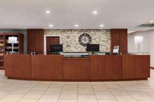 a lobby with a reception desk with a clock on the wall at Wyndham Garden Duluth in Duluth