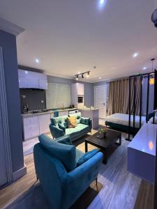 拉各斯Balcony Teal Snug Open-Plan Studio Unit in Lekki Phase 1-Netflix, Wi-Fi, 24-7 Light, Washer, Kitchen的一间带2张蓝色沙发的客厅和一间厨房