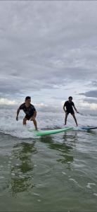 two men are riding on surfboards in the ocean at Blue Cove Villa Varkala in Varkala