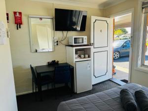 a room with a kitchen with a table and a microwave at Altona Motel in Uralla