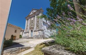 stary kamienny budynek z wieżą z fioletowymi kwiatami w obiekcie Cozy Home In Tinjan With Jacuzzi w mieście Tinjan