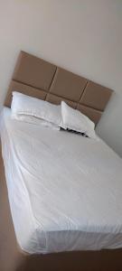 a bed with white sheets and two pillows at Joan's home to many in Kisumu