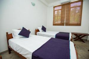 a bedroom with two beds and a window at Singhe Apartment in Galle