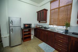 a kitchen with a stainless steel refrigerator and wooden cabinets at Singhe Apartment in Galle