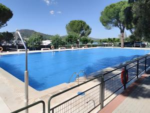 a large swimming pool with a fence around it at Cumbre Escondida in Pelayos de la Presa