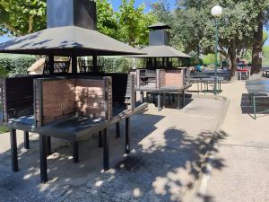a park with benches and a grill with an umbrella at Cumbre Escondida in Pelayos de la Presa