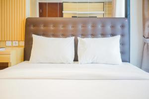 a bed with two white pillows and a brown headboard at Cozy 3BR Asatti Apartment near ICE BSD By Travelio in Tangerang +17 photos