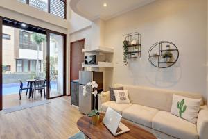 a living room with a couch and a table with a laptop at Cozy 3BR Asatti Apartment near ICE BSD By Travelio in Tangerang