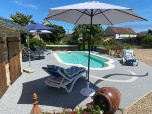 an umbrella and chairs next to a swimming pool at Le Domaine de L étang La saboterie in Oeuilly