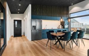 a kitchen and dining room with blue cabinets and a table and chairs at 3 Bedroom Stunning Home In Løgstrup in Løgstrup