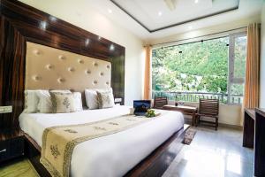 a bedroom with a large bed and a large window at The Bunksters Mcleodganj, Dharmkot in McLeod Ganj +186 photos