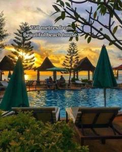 a pool with chairs and umbrellas in a resort at Lanta Beautiful beach house in Ko Lanta