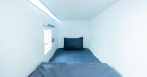 a bedroom with a blue bed in a white room at Bobopod Pancoran, Jakarta in Jakarta