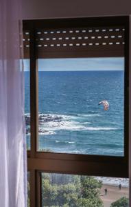 una ventana con vistas al océano y una cometa en Populo Beach Apartment, en São Roque