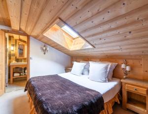 a bedroom with a large bed with a skylight at La Maison Hôtel Les Peupliers in Courchevel +18 photos