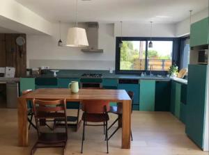 a kitchen with a wooden table and green cabinets at Belle maison entre les sentiers côtiers et la vieille ville in Vannes +18 photos