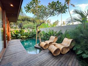 two chairs sitting on a deck next to a pool at Villa Suarga Des Anicca in Ubud