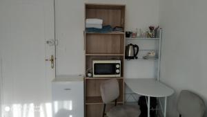 Cette petite chambre comprend un four micro-ondes, une table et des chaises. dans l'établissement CHAMBRE CONFORTABLE,GARE,Climatisation,PARKING,WIFI,pt déjeuner compris, à Perpignan